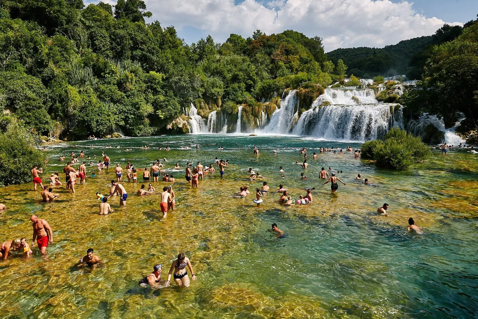 Krka waterfalls at Skradinski buk, visitors swimming in the green water below